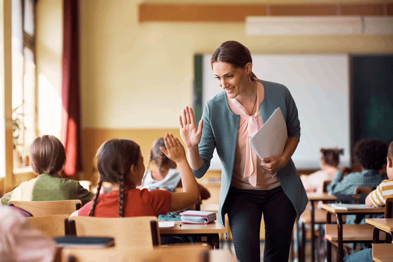Classroom Training | Career Calling International A teacher high-fives a student, demonstrating quality education and training delivery.