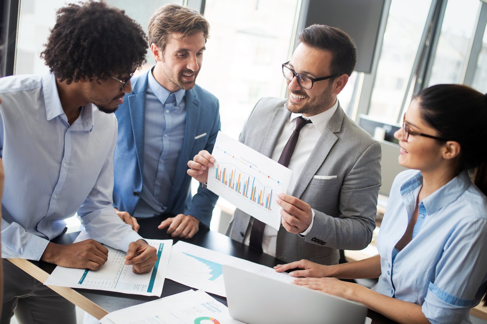 A diverse team collaborates around a table reviewing business data for vet compliance.
