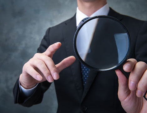 A businessperson uses a magnifying glass to examine assessment evidence, highlighting the importance of vet compliance.