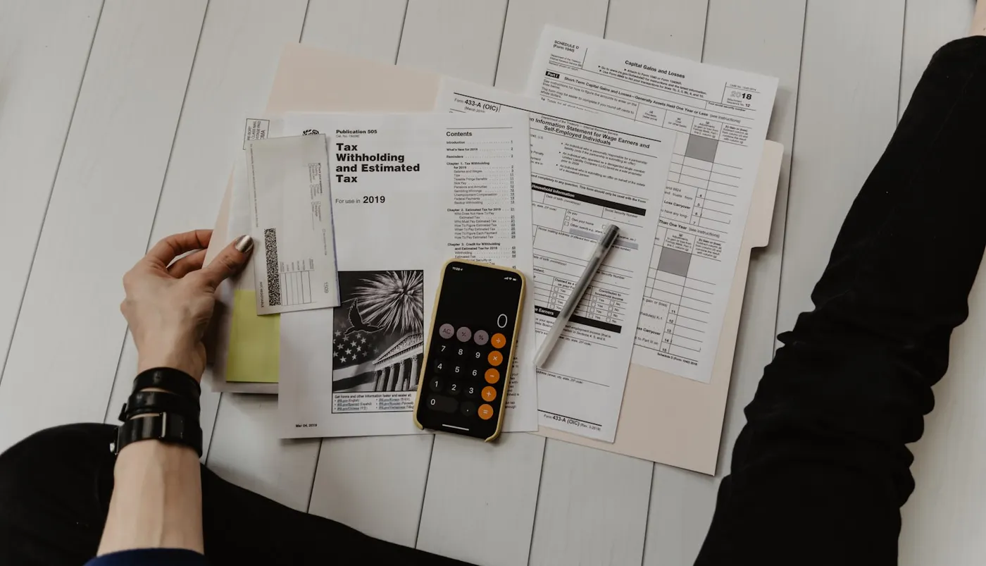 A person prepares taxes with forms, a calculator and pen, illustrating the financial aspects of RPL assessment.