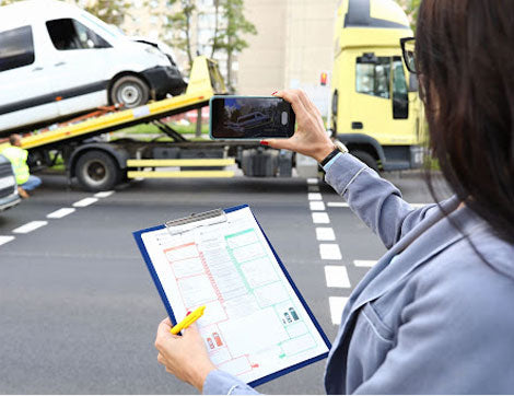 A woman documents vehicle damage after a car accident, relating to compliance and insurance claims.