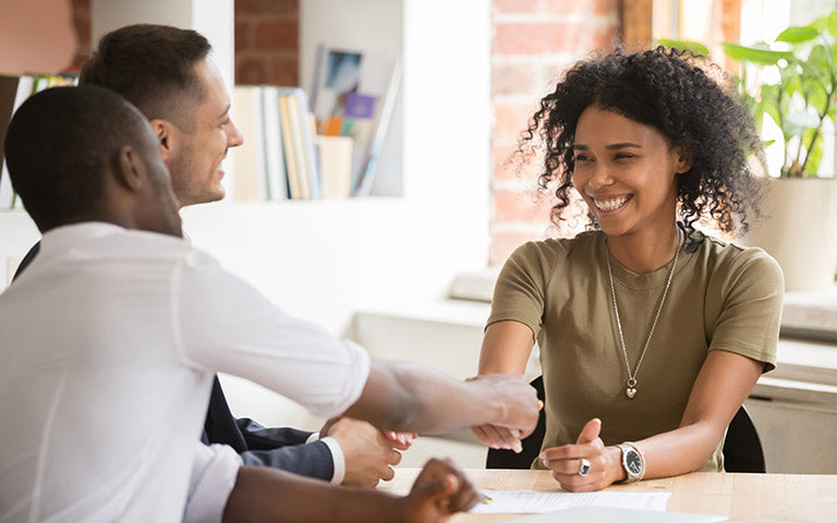 Two people shake hands during a meeting about transitioning to a new training package, demonstrating our vet compliance.
