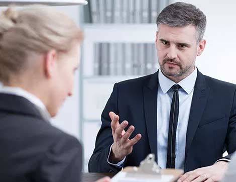 A man interviews a woman during a vet compliance assessment, demonstrating professional training and validation processes.