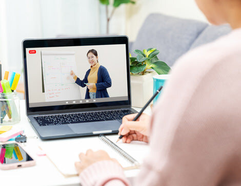 Online Learning | Career Calling International A person takes notes during an online lecture, demonstrating our vocational education training services.