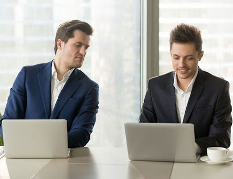 VET News | Career Calling International Two businessmen work on laptops, discussing training resources and vet compliance.